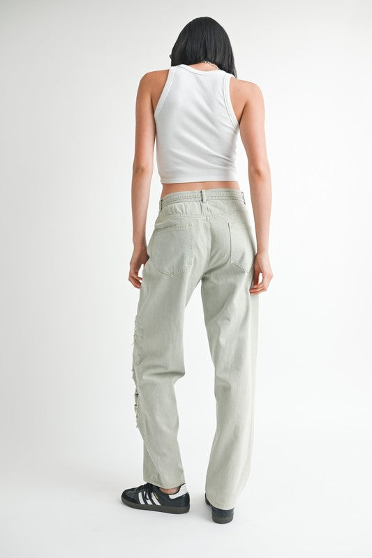 Back view of woman wearing Emory Park distressed wide leg pants in light gray with white tank top and black sneakers