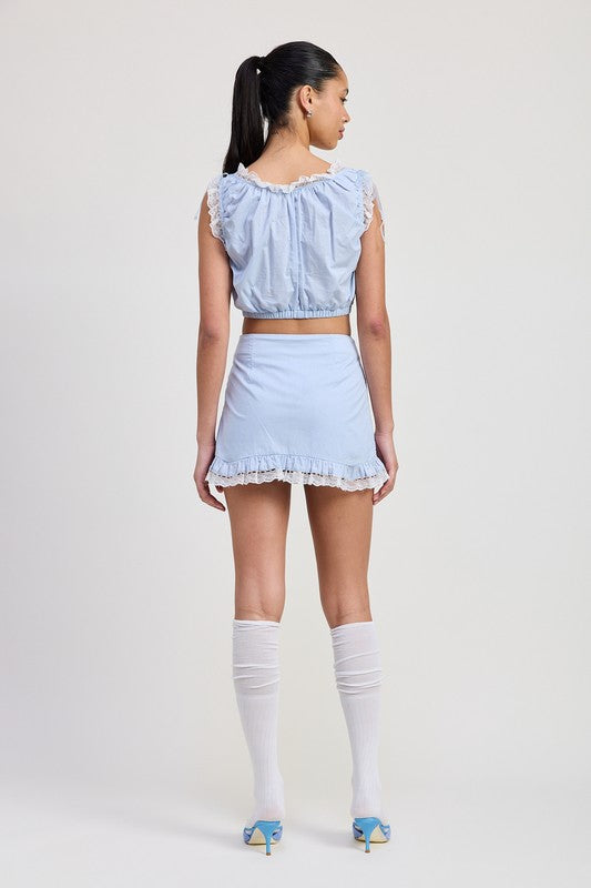 Back view of woman wearing Emory Park sleeveless lace ruffled top in light blue with matching skirt and white knee-high socks