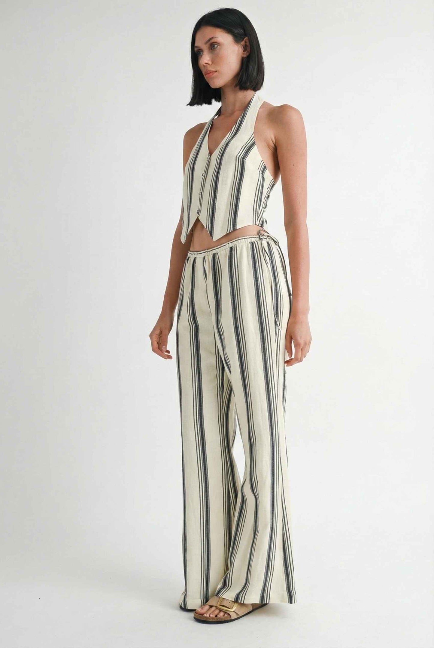Model wearing Arlo Pants inNavy Striped Linen-Viscose Wide-Leg Trousers with matching halter vest and sandals on plain background