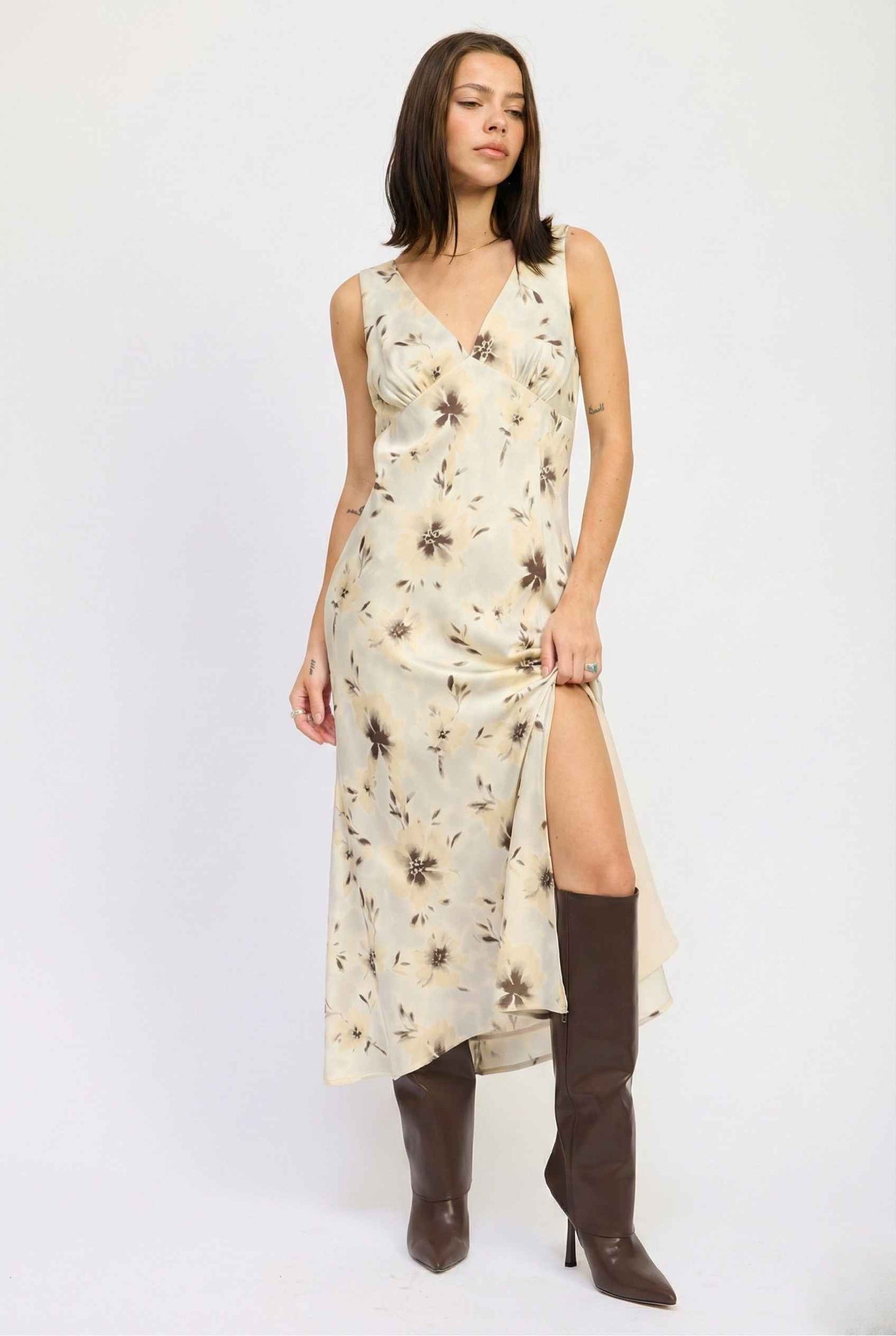 Woman wearing a Aurelia Midi Ivory Sepia Floral V-Neck Slit Dress with a slit and brown knee-high boots on a white background