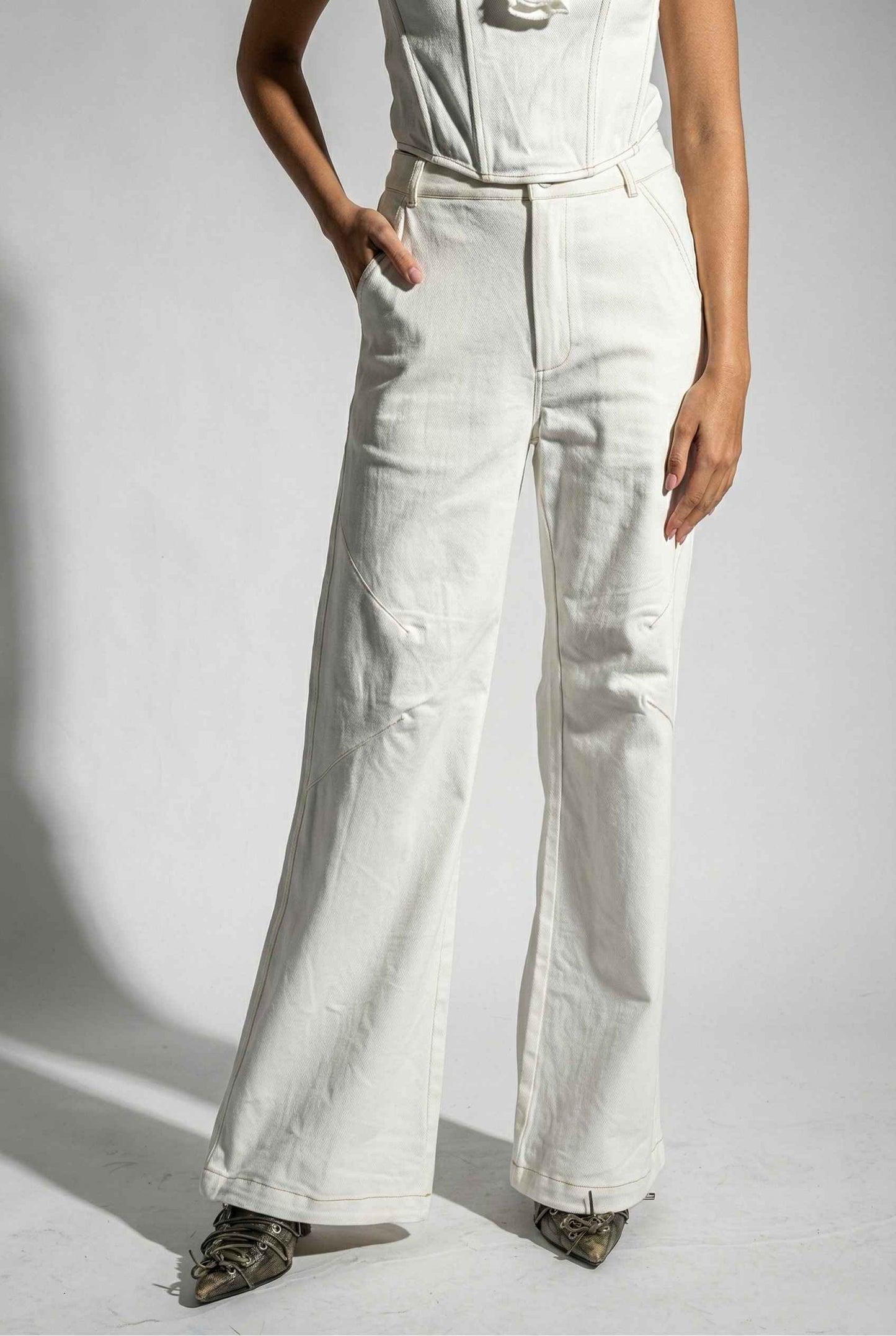 Woman wearing Bianca Pants in Off White Cotton-Stretch Seamed Wide-Leg Trousers and a white top on a plain background