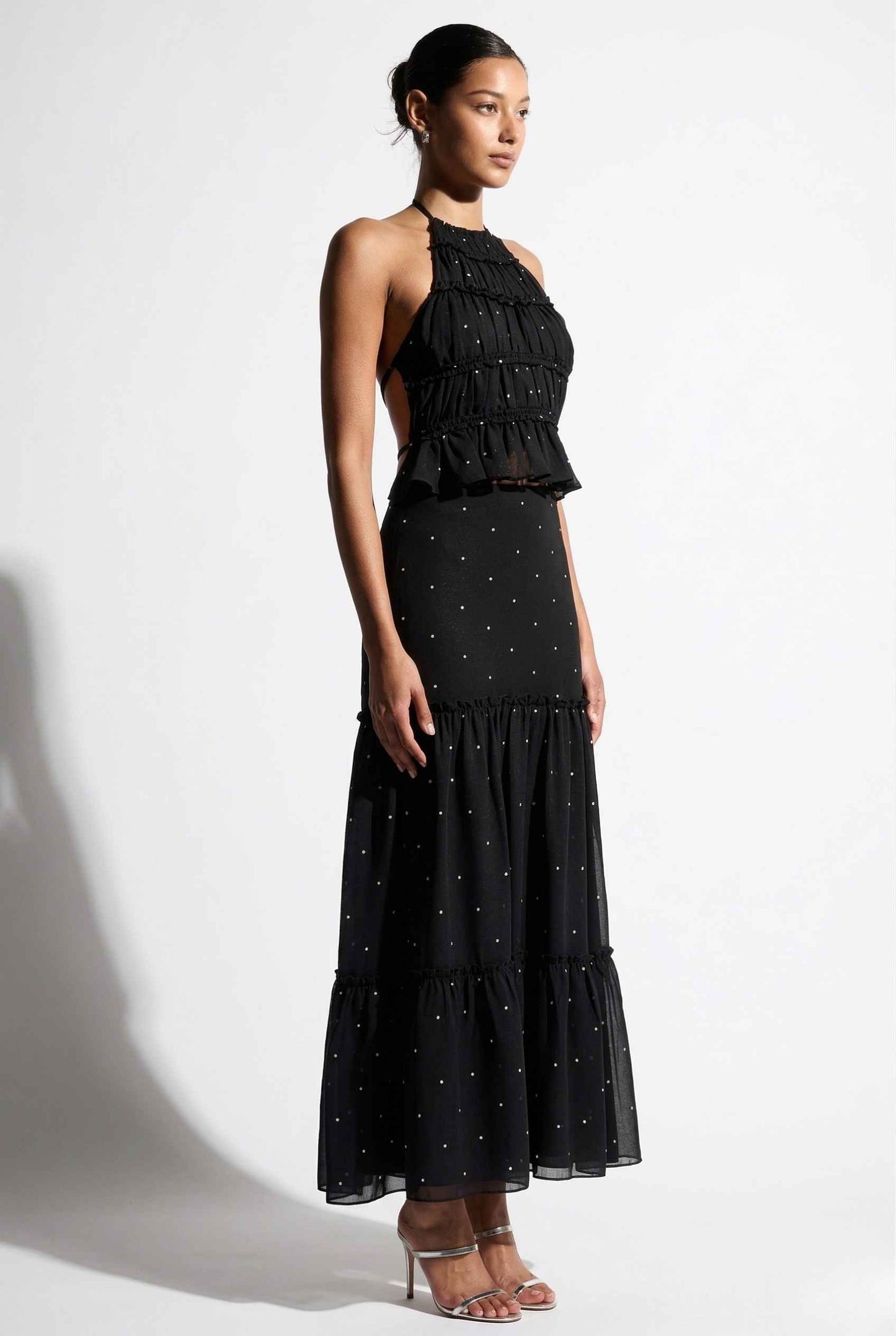 Woman wearing a Clara Skirt Black Tiered Ruffle Polka Dot Midi Skirt with a plain background