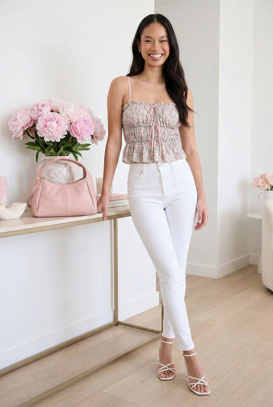 Model wearing Emory Park Floral Tiered Ruffle Top in Pink paired with skinny jeans and strappy sandals standing in minimalist feminine home
