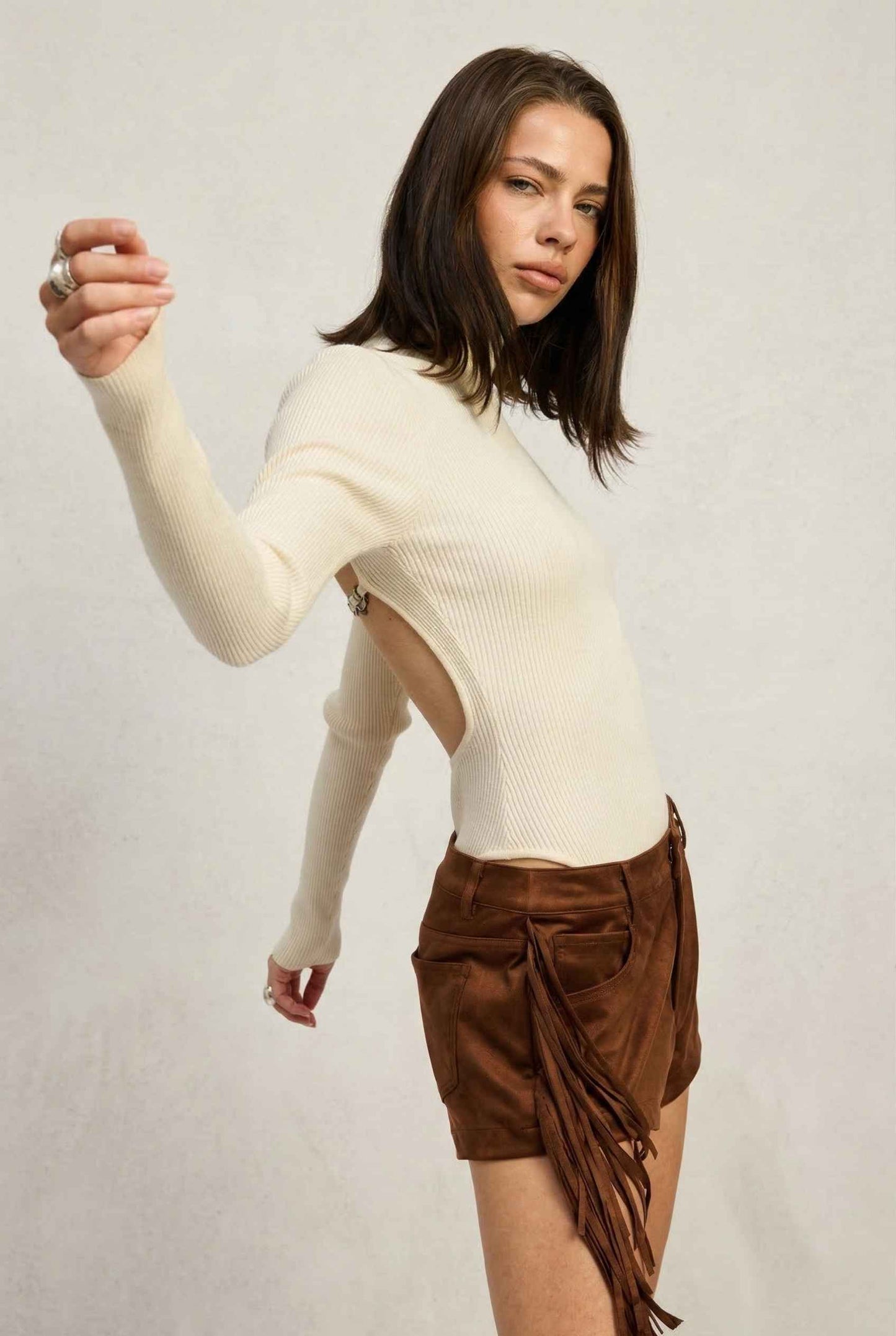 Model wearing Kiera Bodysuit Ribbed Knit Turtleneck Long Sleeve Bodysuit in Ivory with suede shorts