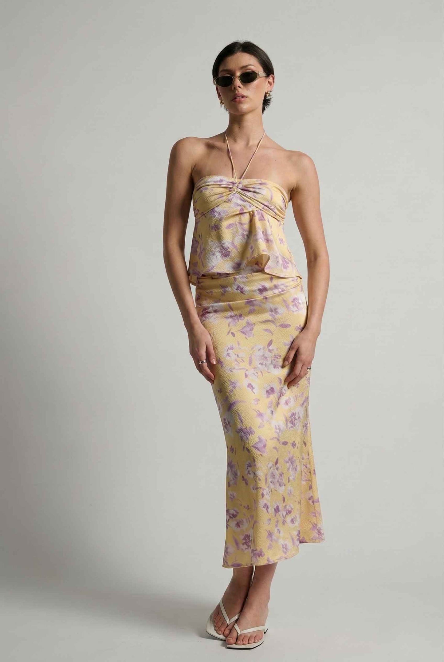 Woman wearing a Liliana Top Yellow & Lilac Floral Halter Peplum posing.