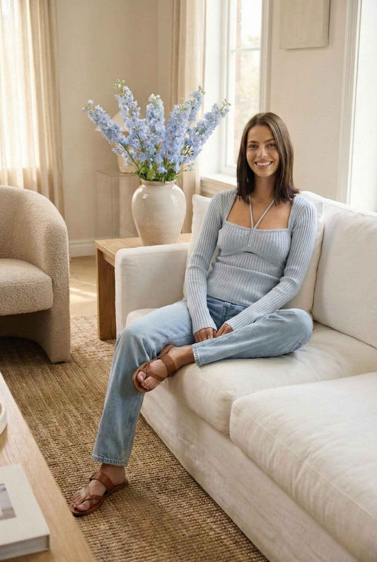Lyra Top in Blue Square Neck Ribbed Knit Top with Halter Strap Detail paired with jeans and leather sandals sitting in living room