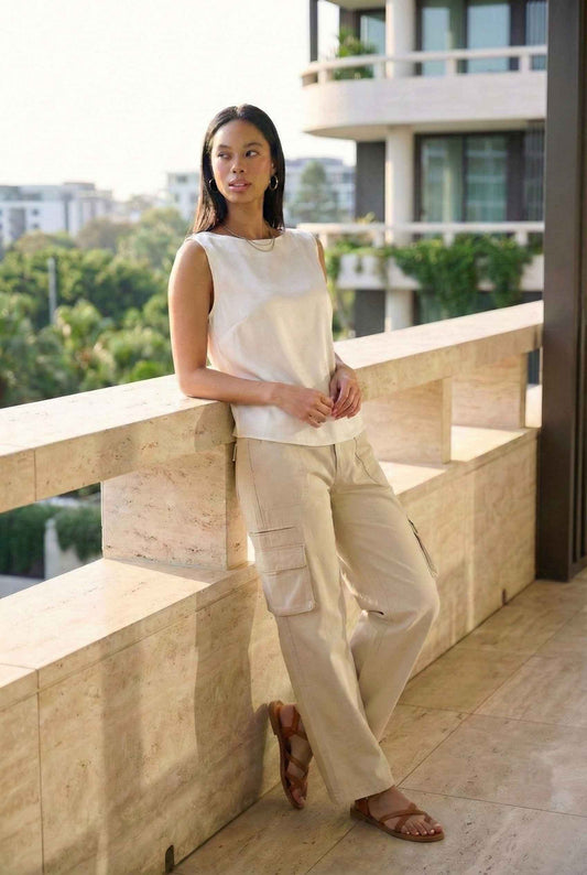 Model wearing Quinn Pants in Stone Beige Cotton Straight-Leg Cargo Trousers with basic tank and sandals standing on luxury balcony