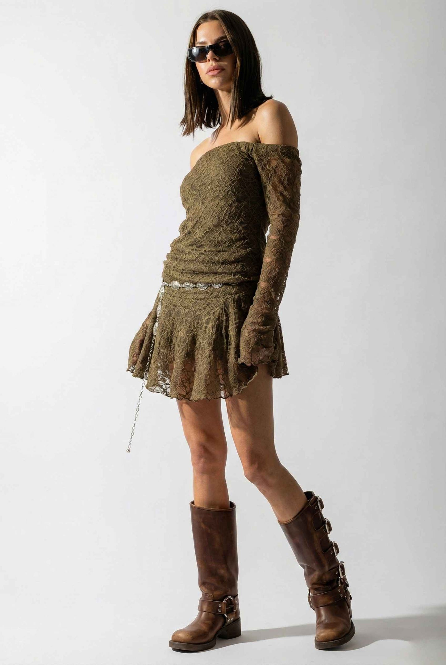 Woman wearing a Rowan Mini Olive Lace Off-Shoulder Long Sleeve Dress and brown boots against a white background