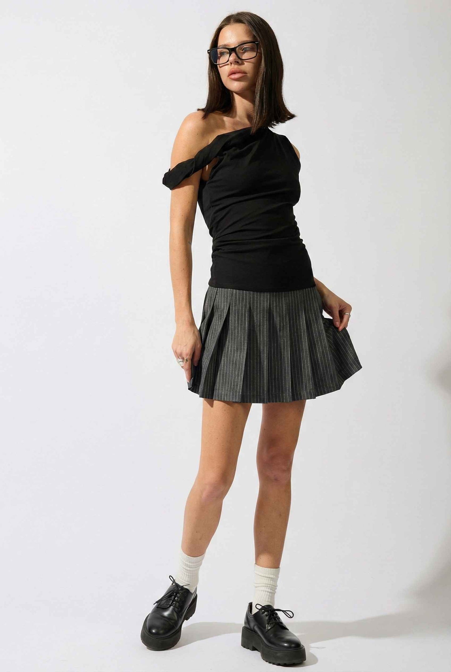 Woman wearing a Sutton Mini Black Asymmetrical Knit & Pinstripe Dress on a white background