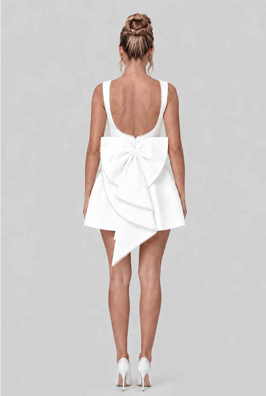 Virtual model wearing The Noemi Pearl Bow Dress Pearl-Trimmed Statement Bow Mini Dress in White