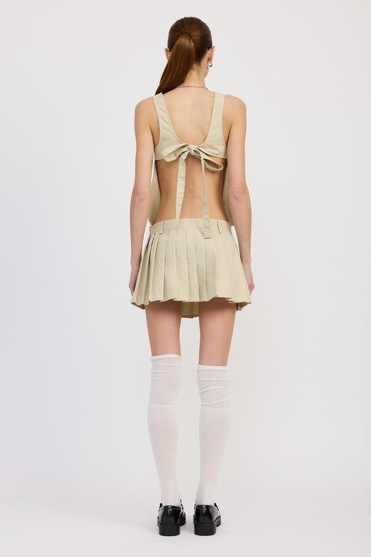 Emory Park Backless Rider Top in beige with open back and tie detail paired with pleated skirt