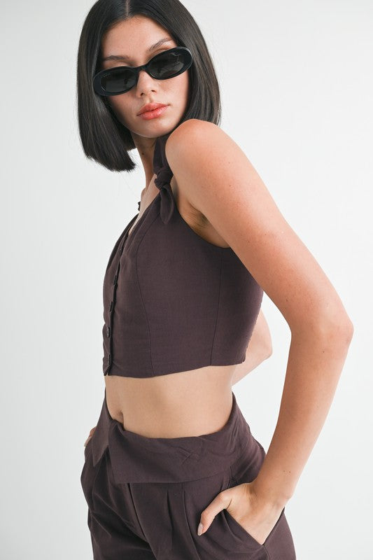 Emory Park Button Up Cropped Top With Shoulder Ties in dark brown worn by model with sunglasses