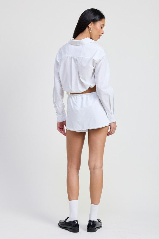 Back view of a woman wearing Emory Park white Cinched Mini Skort With Drawstring paired with a cropped white shirt
