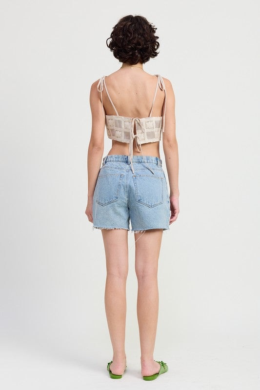Back view of woman wearing Emory Park Cropped Crochet Top with denim shorts and green sandals