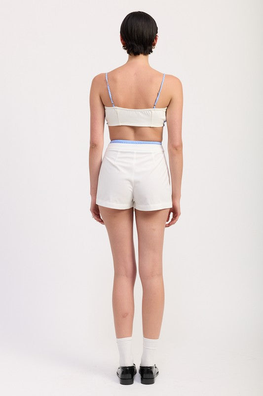 Back view of model wearing Emory Park Pleated Contrast Trim Skort in white with blue trim details