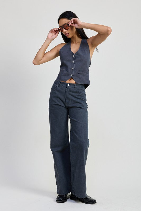 Model wearing Emory Park folded fitted denim pants in dark wash with sleeveless buttoned vest and sunglasses