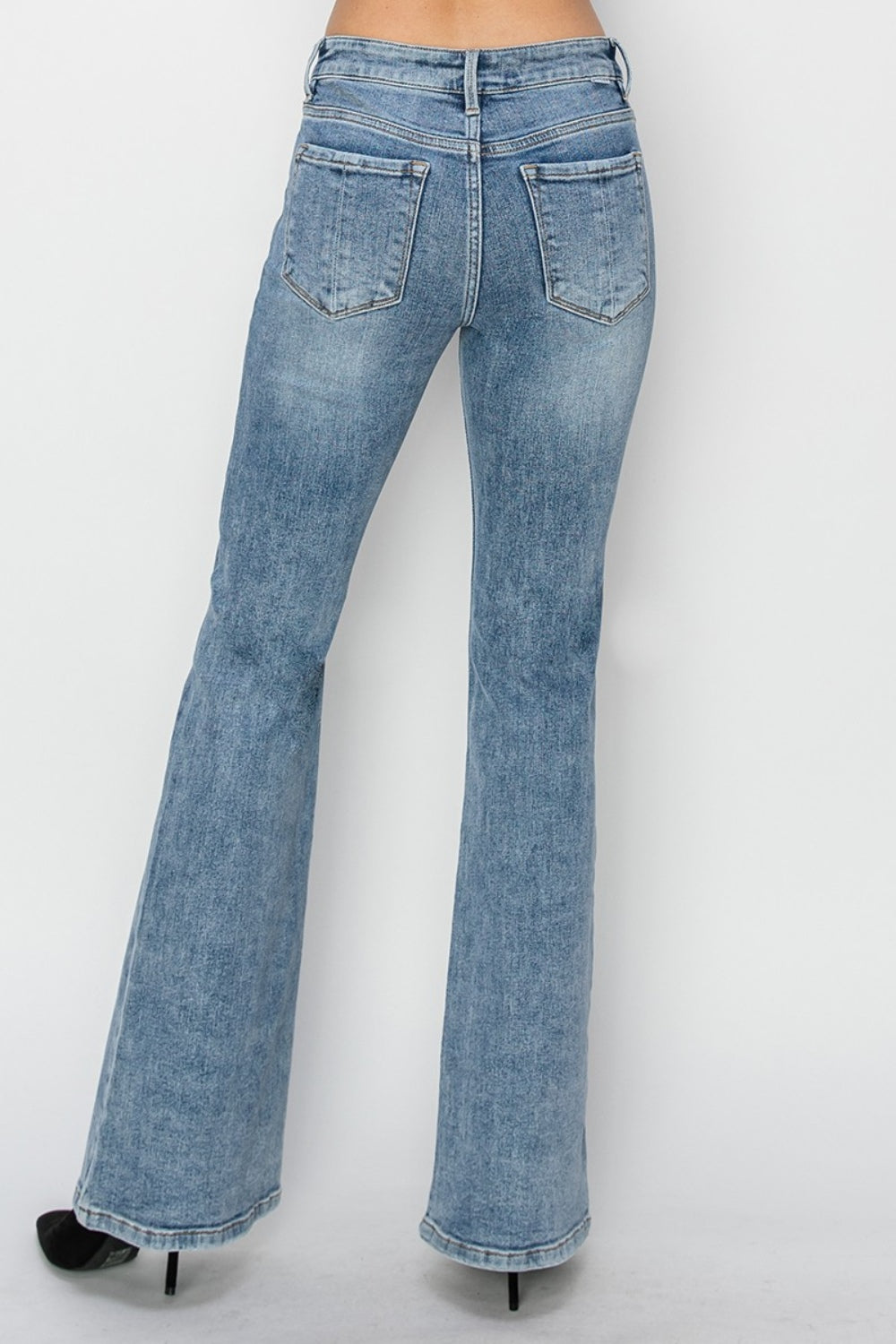 Back view of mid-rise bootcut jeans in light wash denim with flared legs