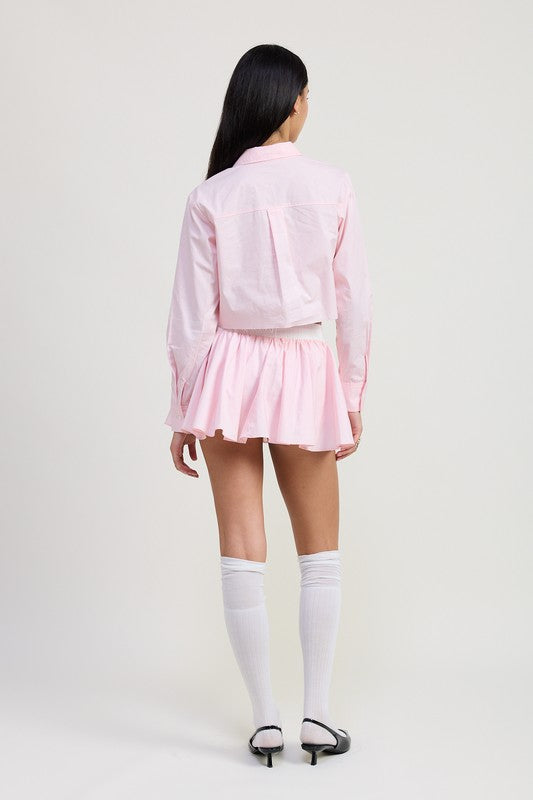 Back view of a woman wearing Emory Park Mini Contrast Waistband Skirt in pink with white knee-high socks and black heels