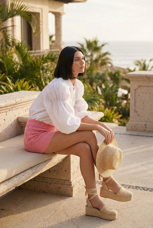Model wearing Emory Park pink Mini Crochet Skirt with white blouse espadrilles sitting outside luxury resort