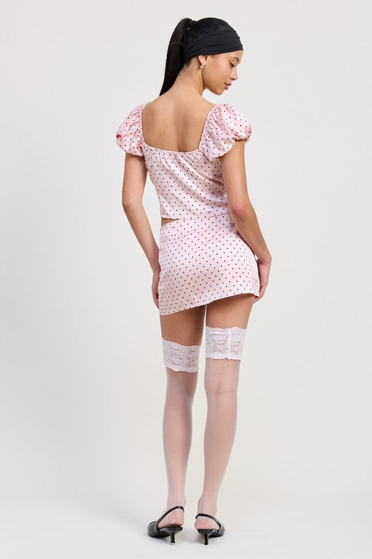 Woman wearing Emory Park Mini Polka Dot Skort in pink with puff sleeves and black polka dots