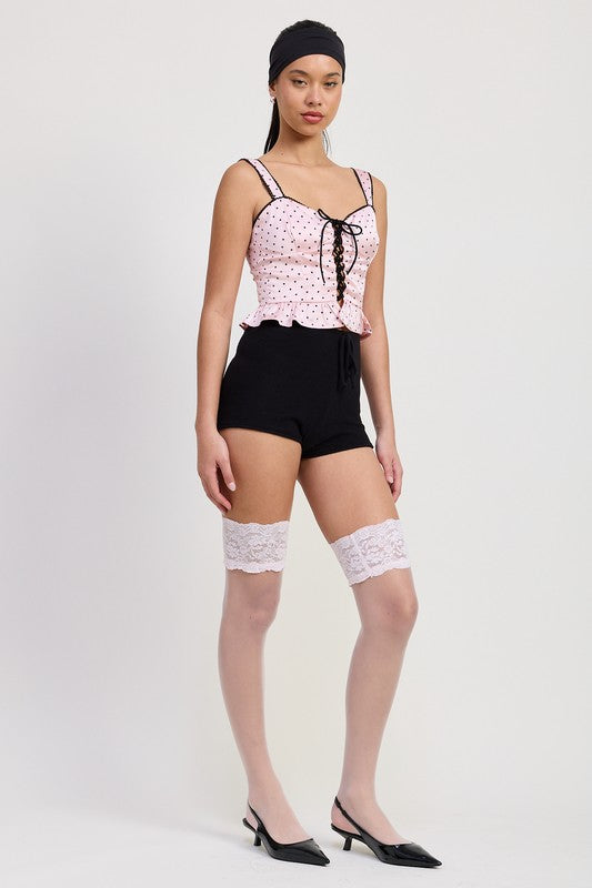 Emory Park Polka Dot Corset Top in pink with black dots worn with black shorts and lace thigh-high stockings