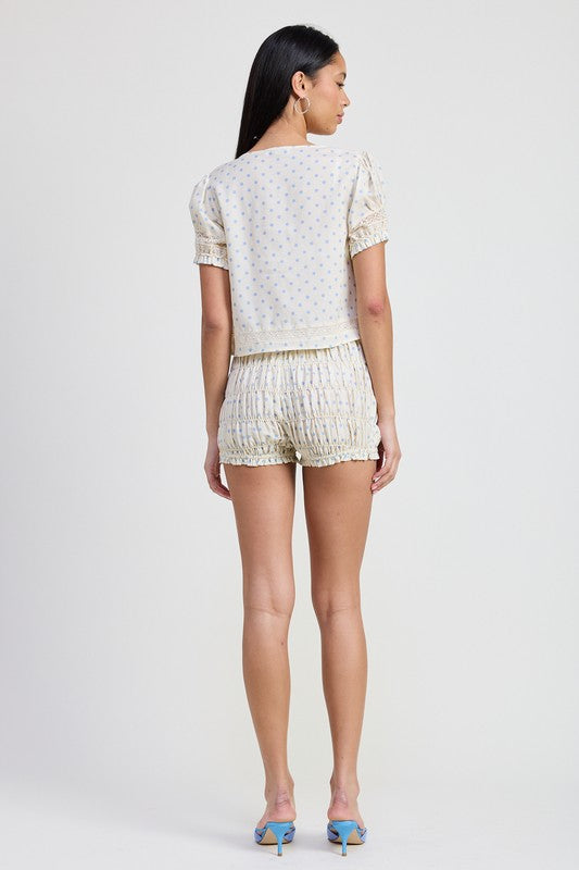 Back view of woman wearing Emory Park Puff Sleeve Tie Front Top with matching shorts and blue heels