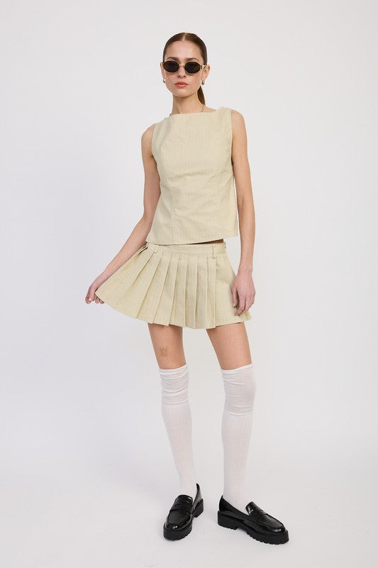 Model wearing Emory Park Rider Mini Skort in beige pleated style with matching sleeveless top and black loafers