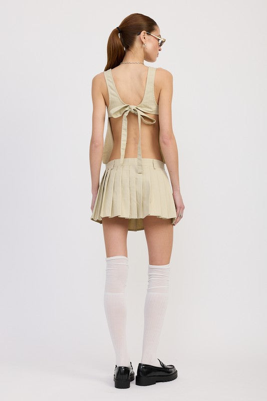Back view of a model wearing Emory Park beige Rider Mini Skort with pleats and an open back top