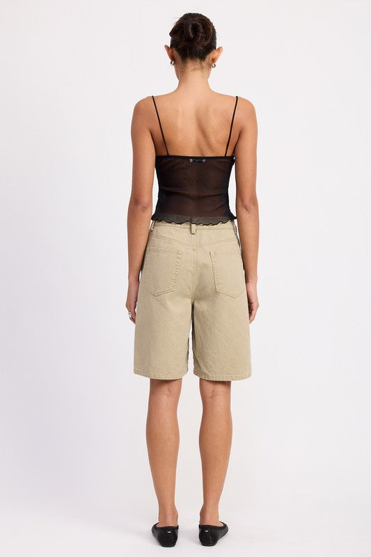 Back view of model wearing Emory Park Sheer Mesh Floral Cup Cami Top in black with beige knee length shorts