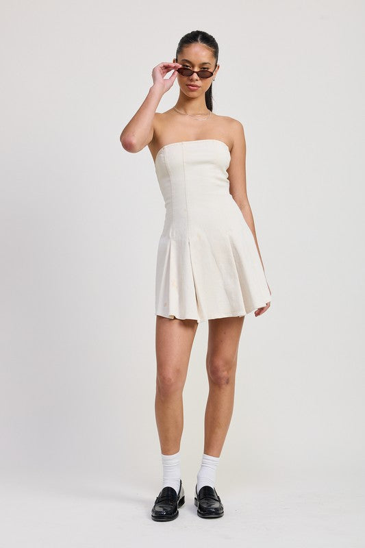 Emory Park strapless mini ruffle dress in cream worn with black loafers and sunglasses