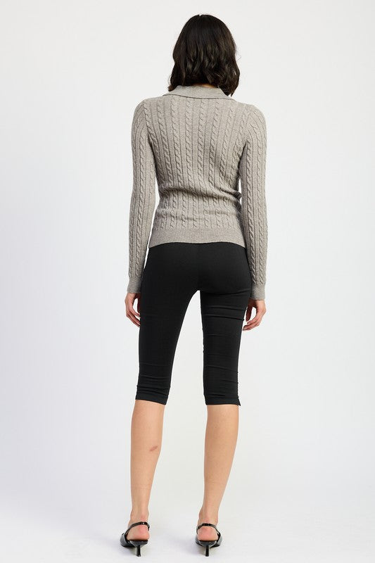 Back view of model wearing Emory Park Cable Knit Cardigan Top in gray paired with black capri leggings and sandals