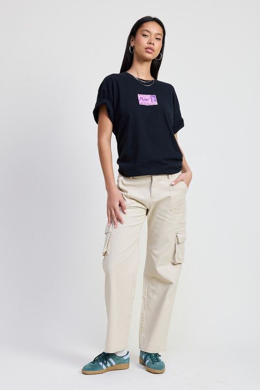 Emory Park model wearing beige Pocket Cargo Pants with side flap pockets paired with black tee and green sneakers