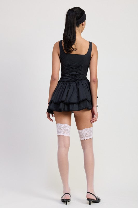 Back view of Emory Park Mini Asymmetrical Sleeveless Dress in black worn with white lace thigh-high stockings