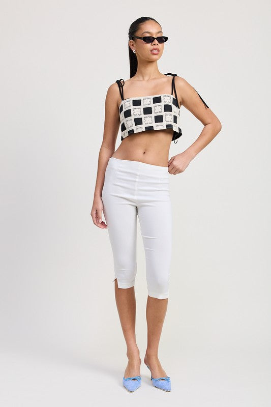 Woman wearing Emory Park black and white checkered Cropped Crochet Top with white capri pants and blue heels