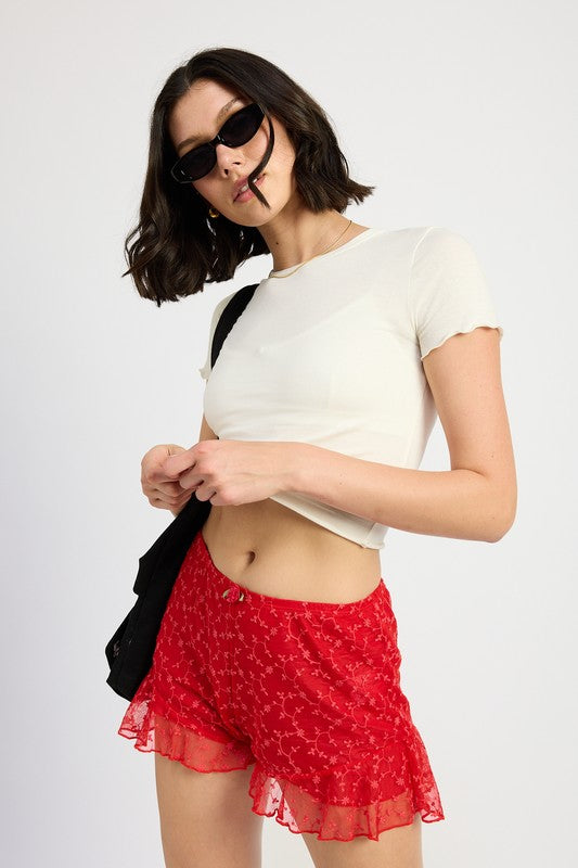 Emory Park Ruffle Jersey Shorts in red with floral pattern worn with white cropped top and black sunglasses