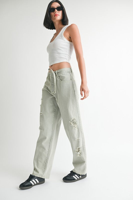Woman wearing Emory Park distressed wide leg pants with a white tank top and black sneakers
