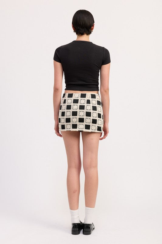 Back view of a woman wearing Emory Park Mini Jacquard Skirt with black and white checkered pattern