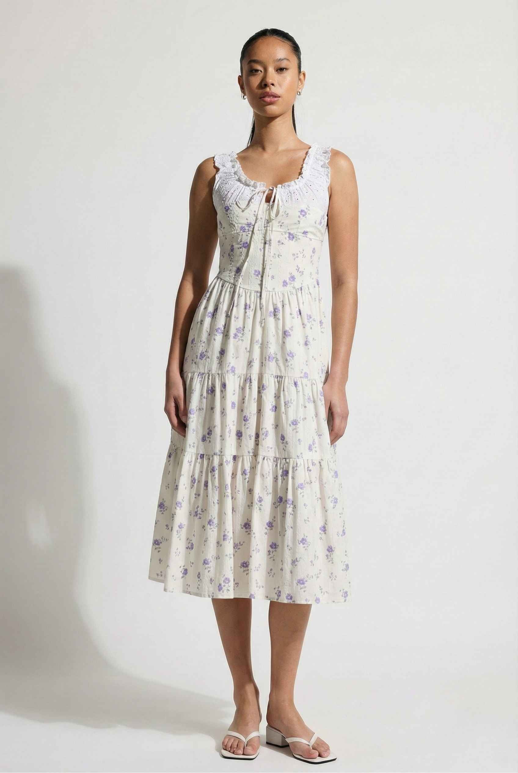 Woman wearing a Adeline Midi | Ivory Floral Eyelet Tiered Dress against a white background