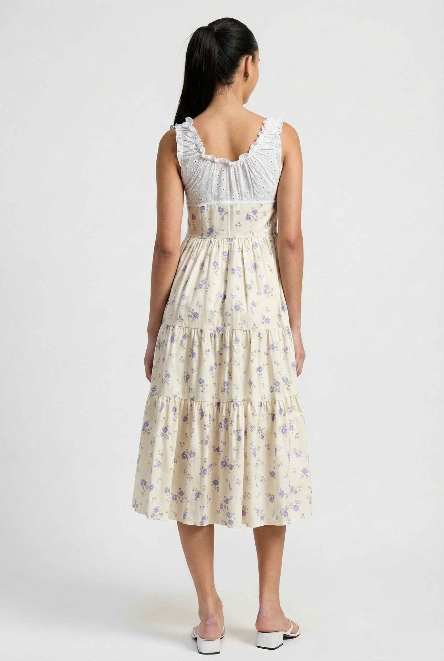 Woman wearing a Adeline Midi | Ivory Floral Eyelet Tiered Dress with floral pattern on a white background