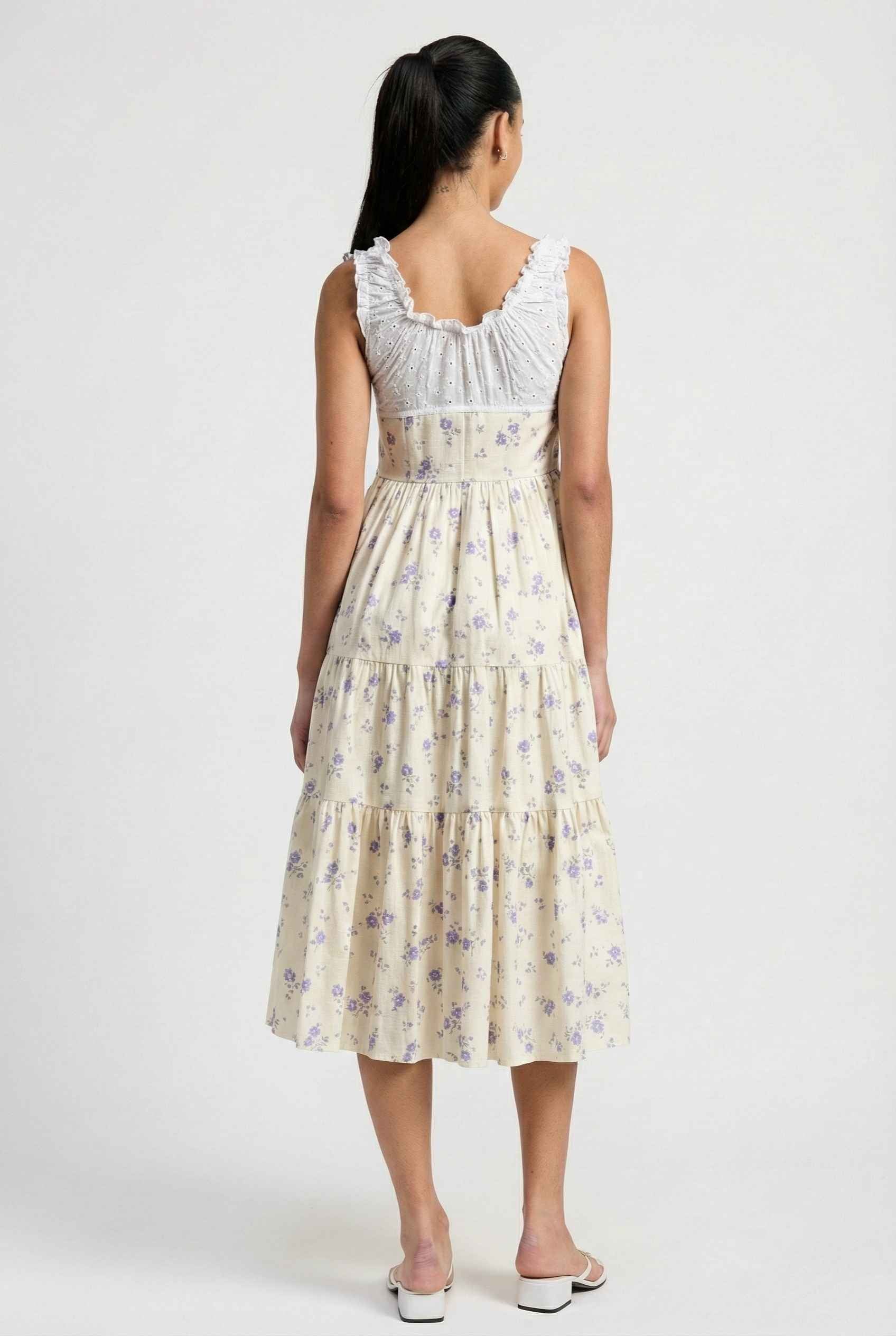 Woman wearing a Adeline Midi | Ivory Floral Eyelet Tiered Dress with floral pattern on a white background