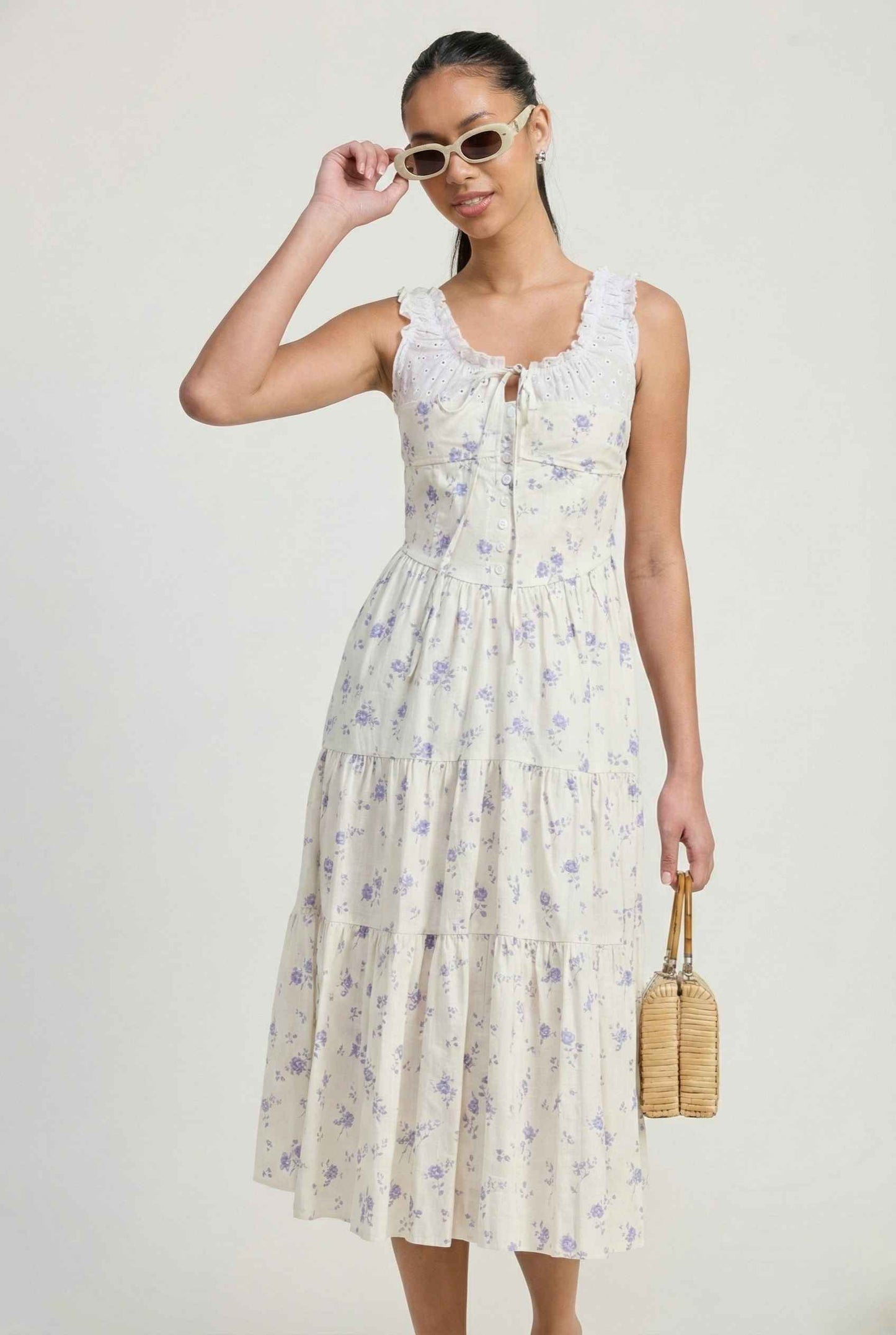 Woman wearing a Adeline Midi | Ivory Floral Eyelet Tiered Dress holding sunglasses against a plain background
