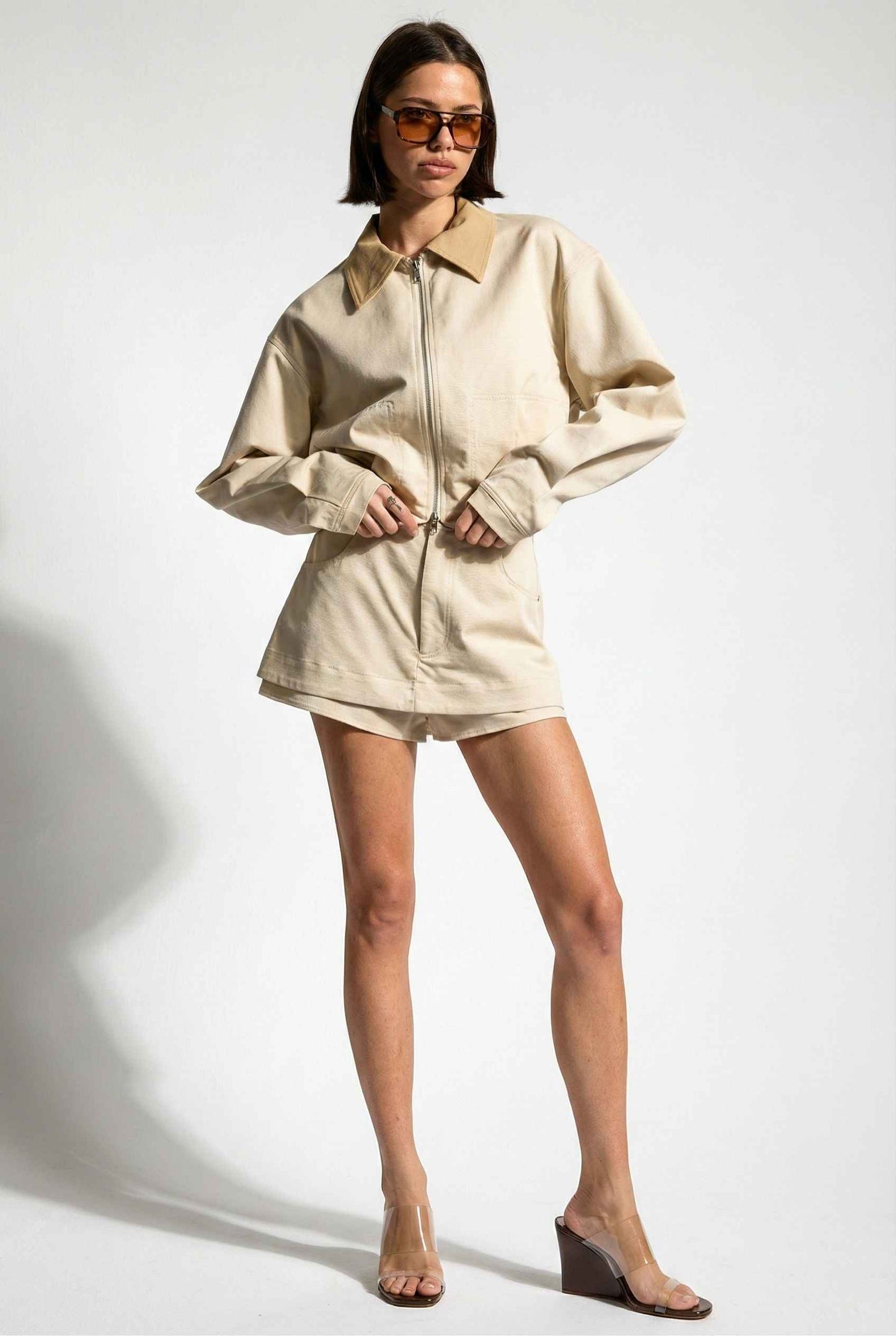 Model wearing Arlo Jacket | Beige Lyocell-Blend Jacket with Contrast Collar with striped shirt and shorts and wedge heels