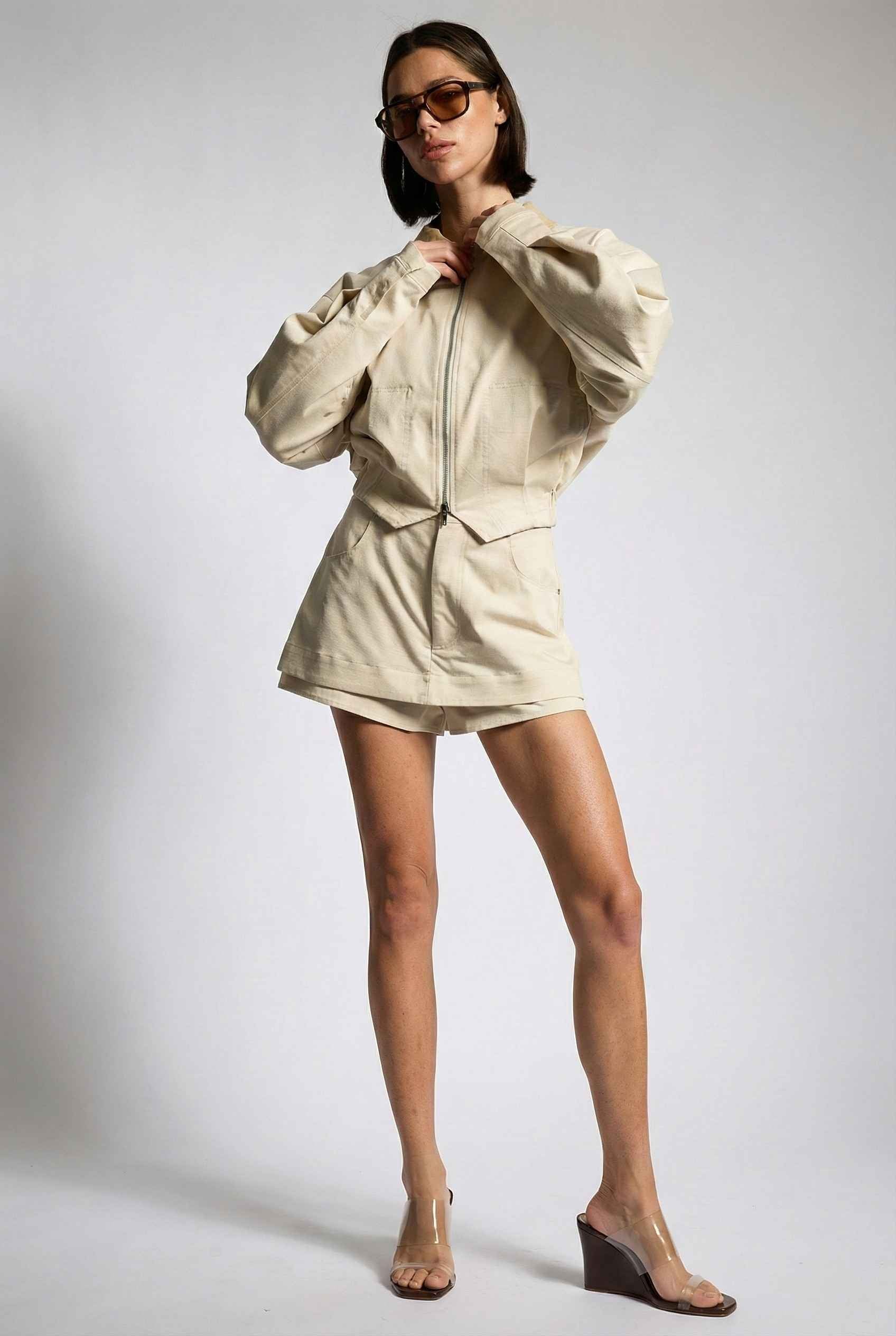 Model wearing Arlo Jacket | Beige Lyocell-Blend Jacket with Contrast Collar with striped shirt and shorts and wedge heels