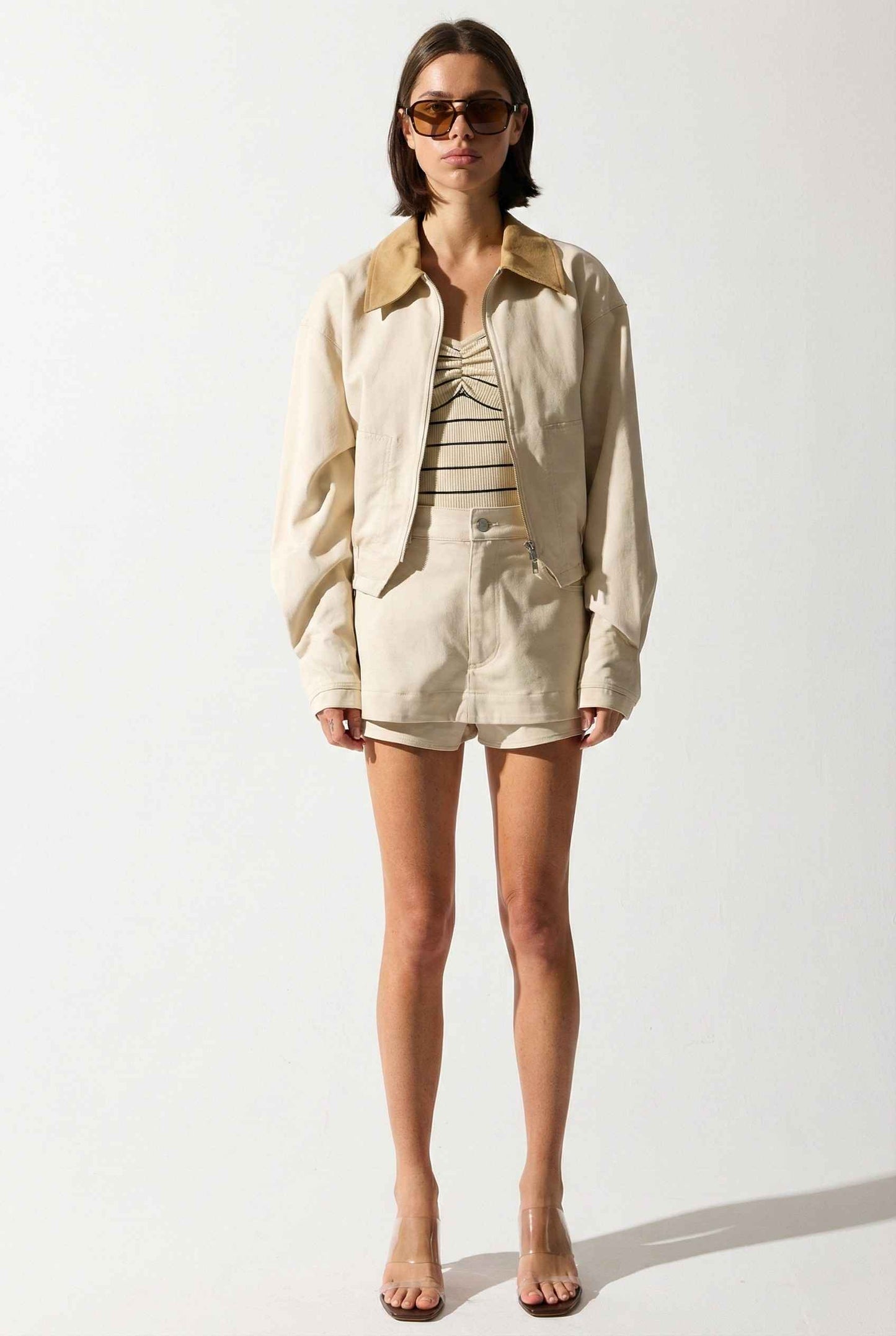 Model wearing Arlo Jacket | Beige Lyocell-Blend Jacket with Contrast Collar with striped shirt and shorts and wedge heels