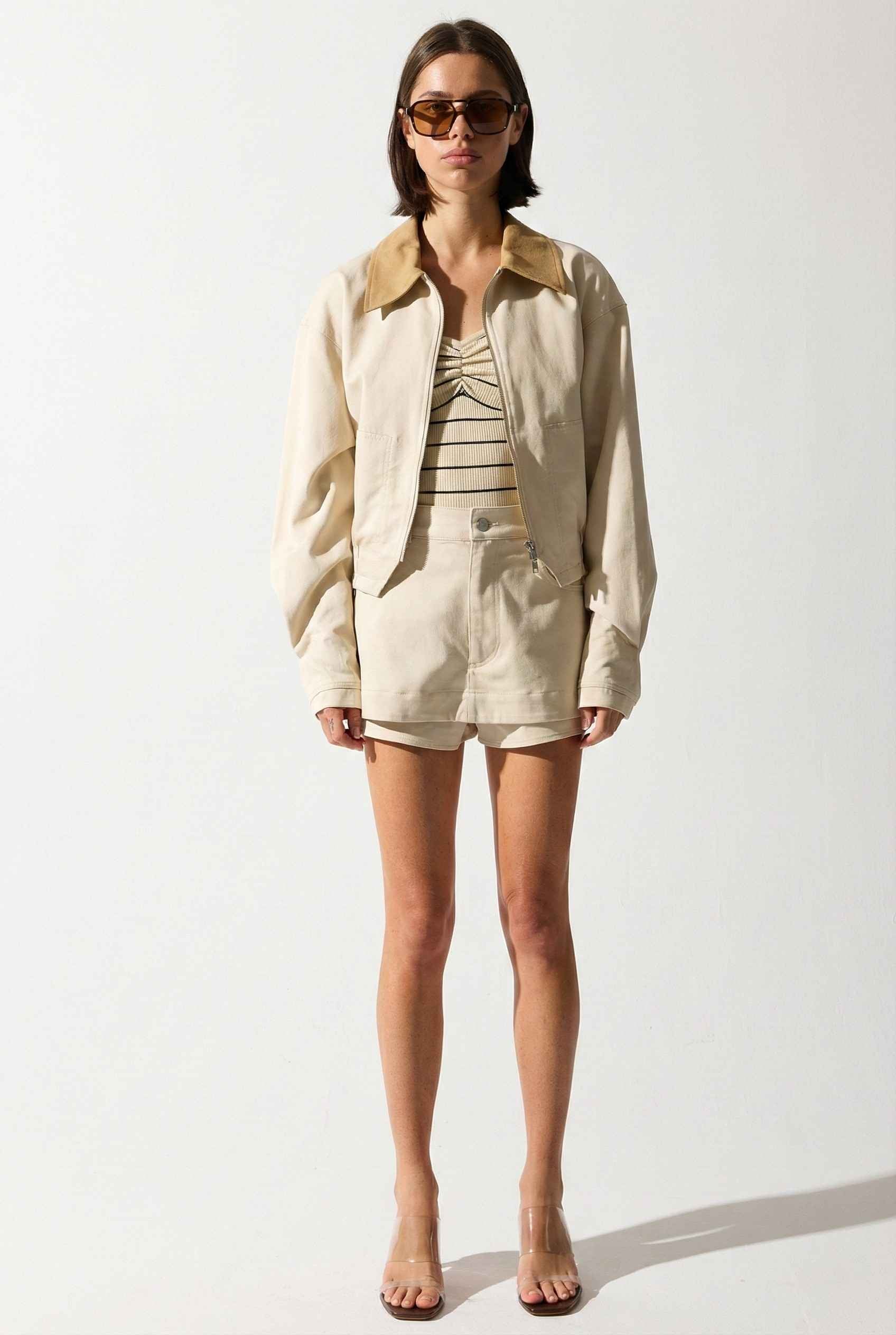 Model wearing Arlo Jacket | Beige Lyocell-Blend Jacket with Contrast Collar with striped shirt and shorts and wedge heels