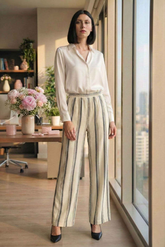 Model wearing Arlo Pants inNavy Striped Linen-Viscose Wide-Leg Trousers with blouse and heels standing in luxury office