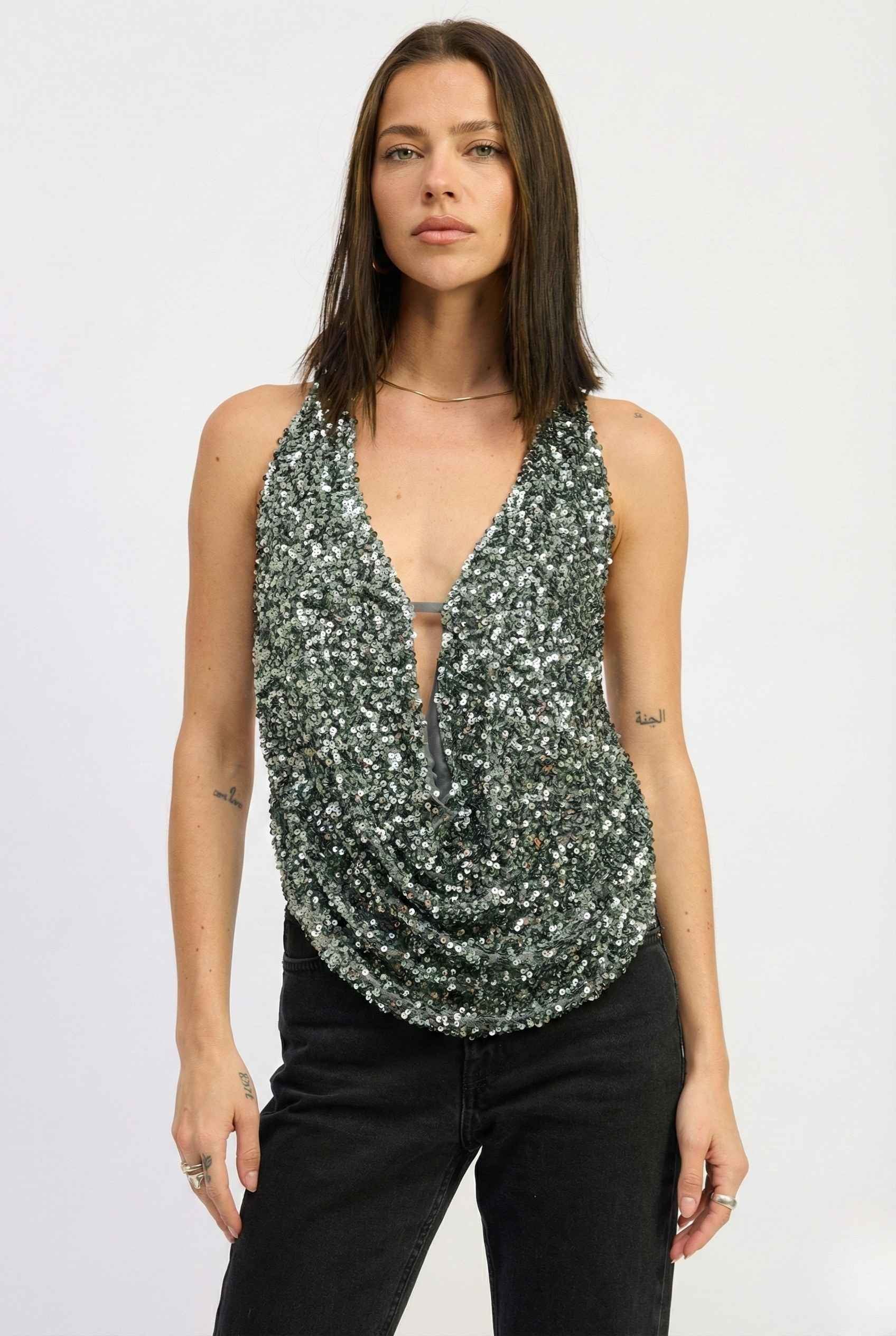 Woman wearing a Astra Top Silver Sequin Draped Halter Neck against a white background