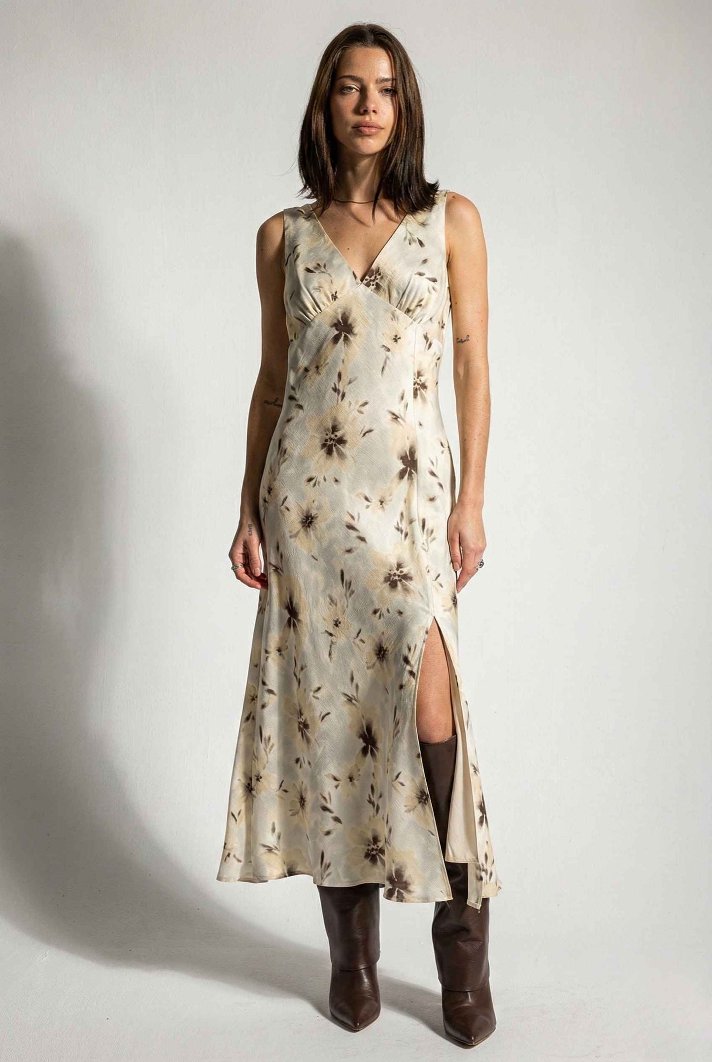 Woman wearing a Aurelia Midi Ivory Sepia Floral V-Neck Slit Dress with a slit on a plain background