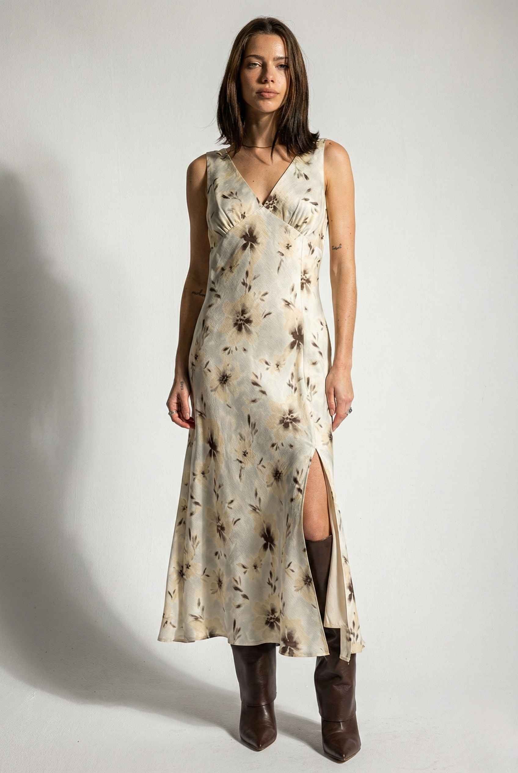 Woman wearing a Aurelia Midi Ivory Sepia Floral V-Neck Slit Dress with a slit on a plain background
