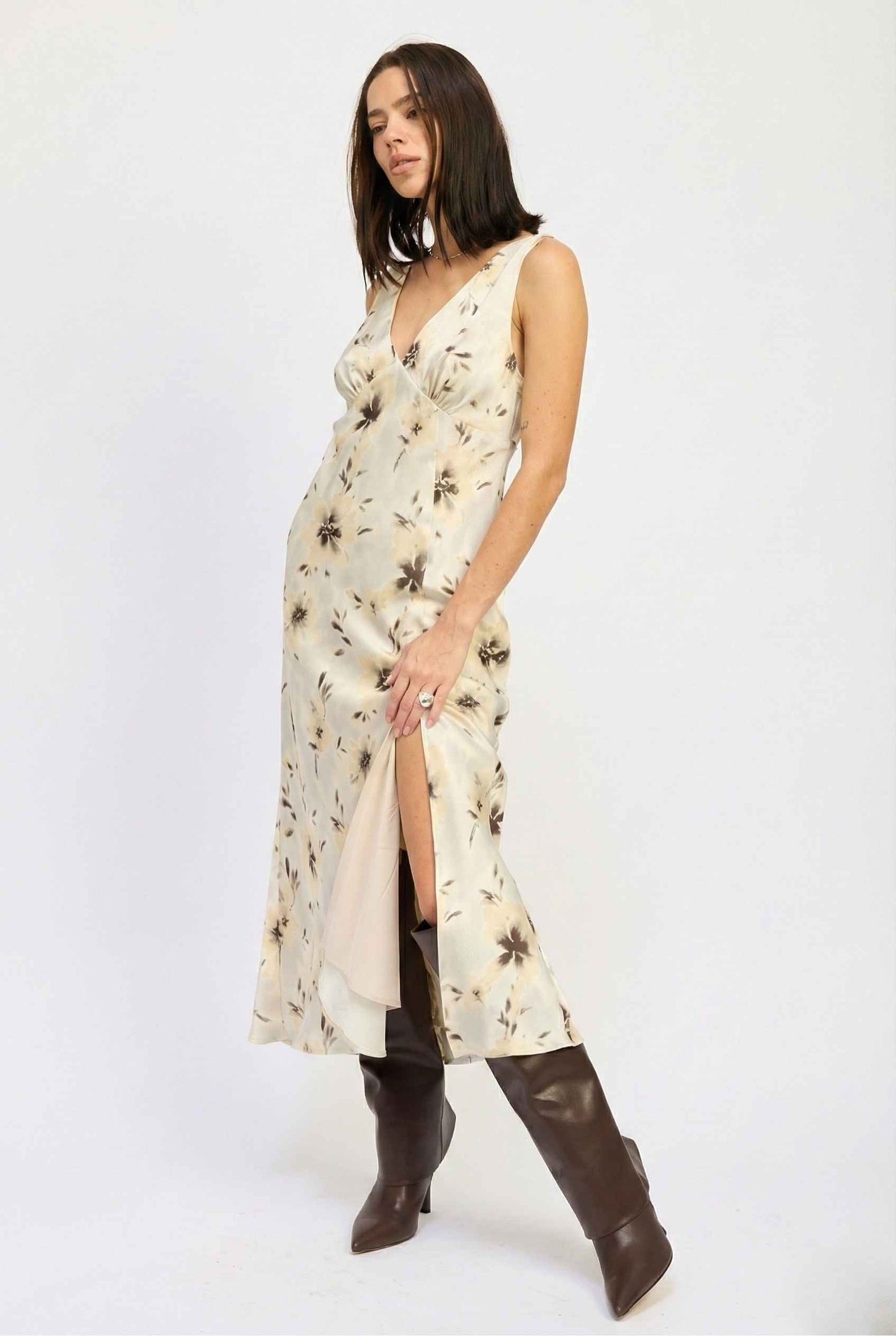 Woman wearing a Aurelia Midi Ivory Sepia Floral V-Neck Slit Dress with a slit and brown boots on a white background
